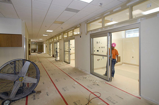 Occupied hospital corridor with temporary containment barriers and a negative air machine